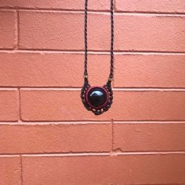 collar_khali_macrame collar khali con piedra obsidiana y sobre fondo de ladrillo